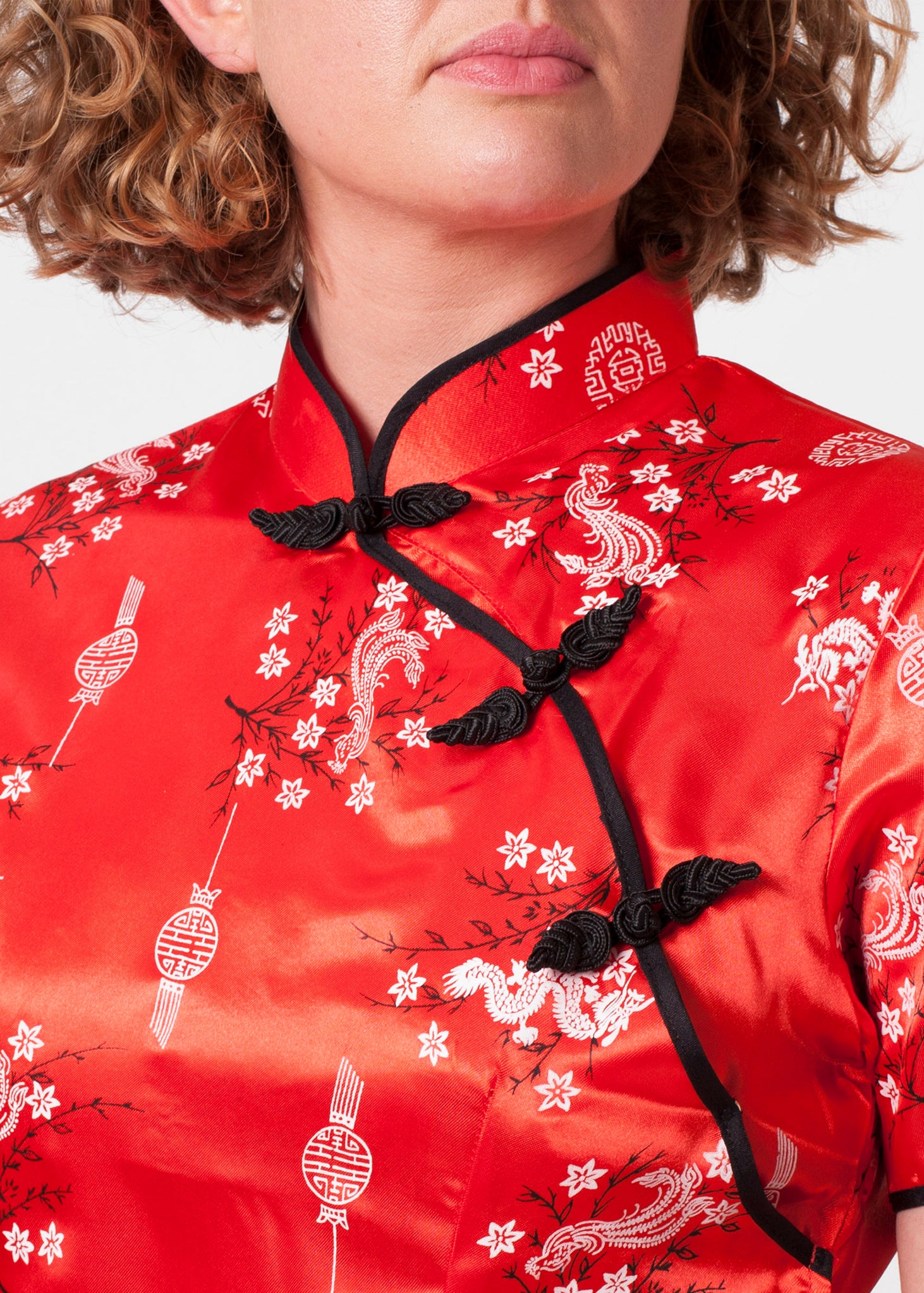 Bound edge mandarin collar and aysmmetric fastening which closes with contrasting flower and knot frog fastenings 