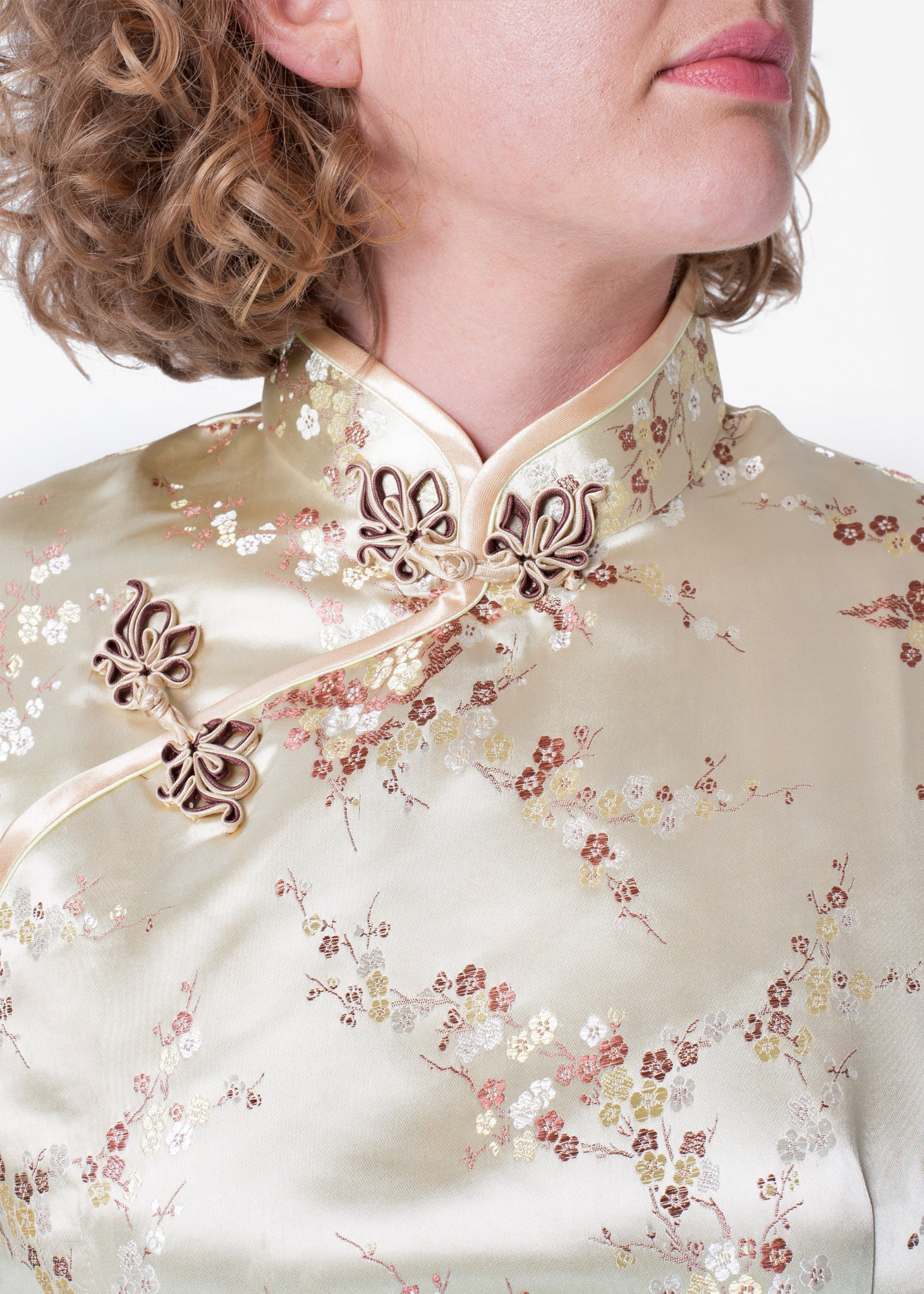 Bound edge mandarin collar and aysmmetric fastening which closes with hand stitched flower and knot frog fastenings in an accent shade