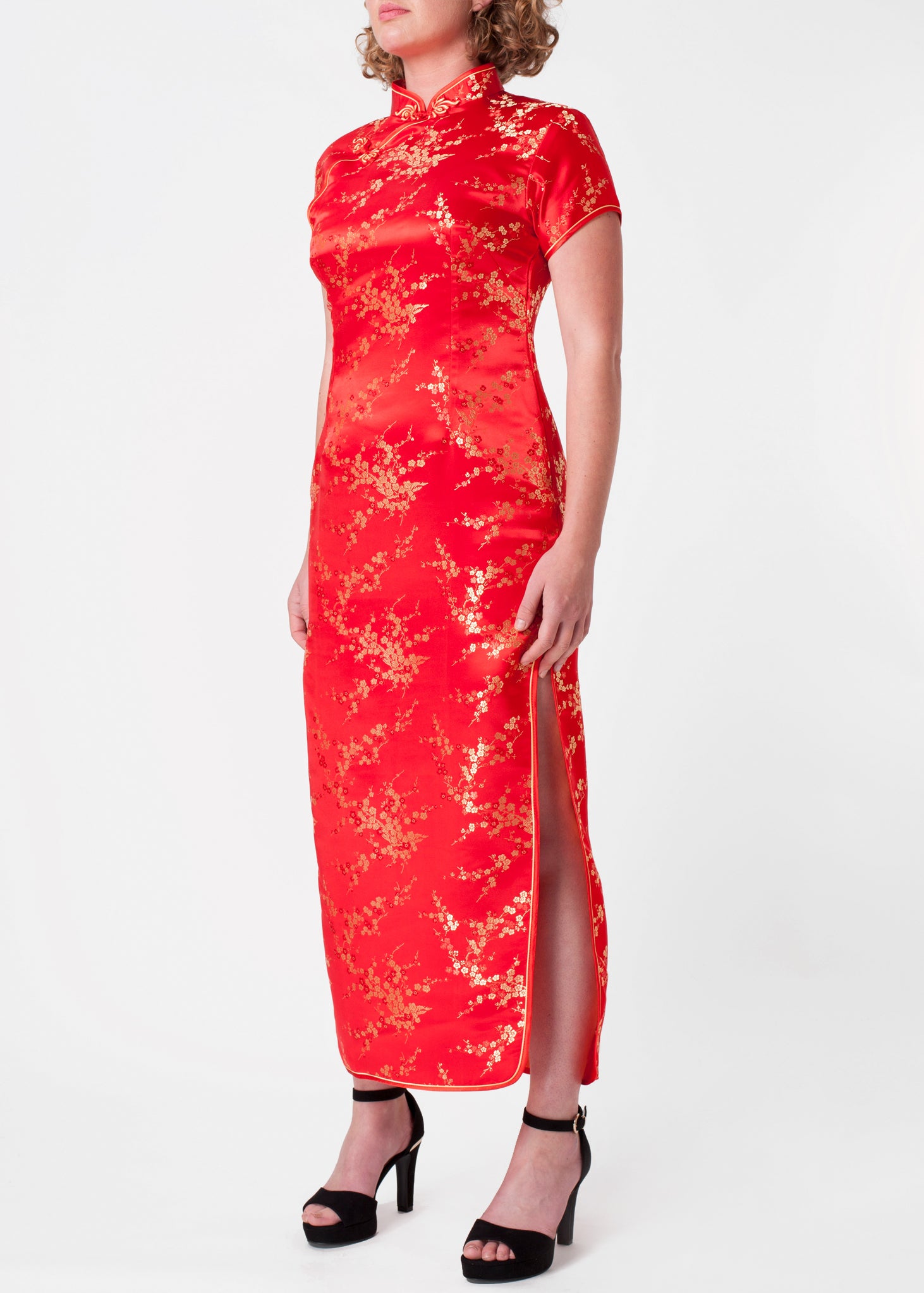 The Cheongsam or Qipao, is a feminine body-hugging Chinese style dress with distinctive features of mandarin collar, side splits and hand stitched flower and knot frog fastenings. Manufactured in authentic high quality silk/rayon brocade in a stunning red with gold cherry blossom design. Quick delivery from UK stock