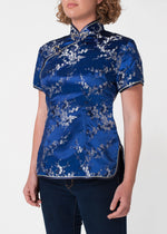 Traditional Chinese blouse in Cheongsam or Qipao style with distinctive Chinese features of mandarin collar, hand stitched flower and knot frog fastenings and side zip. Manufactured in authentic high quality silk/rayon brocade in rich blue and silver cherry blossom design - a symbol of female beauty and love.