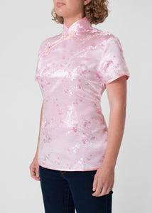 Traditional Chinese blouse in Cheongsam or Qipao style with distinctive Chinese features of mandarin collar, hand stitched flower and knot frog fastenings and side zip. Manufactured in authentic high quality silk/rayon brocade in a delicate shell pink cherry blossom design - a symbol of female beauty and love.