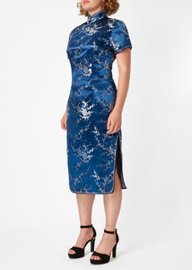 The Cheongsam or Qipao, is a feminine body-hugging dress with distinctive Chinese features of mandarin collar, side splits and hand stitched flower and knot frog fastenings. Manufactured in authentic high quality silk/rayon brocade in a rich blue with silver cherry blossom design - a symbol of female beauty and love.